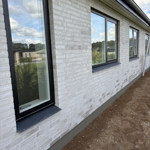 Murerarbejde på facade i Aarhus med lyse mursten og sorte vinduesrammer.