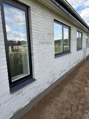 Murerarbejde på facade i Aarhus med lyse mursten og sorte vinduesrammer.